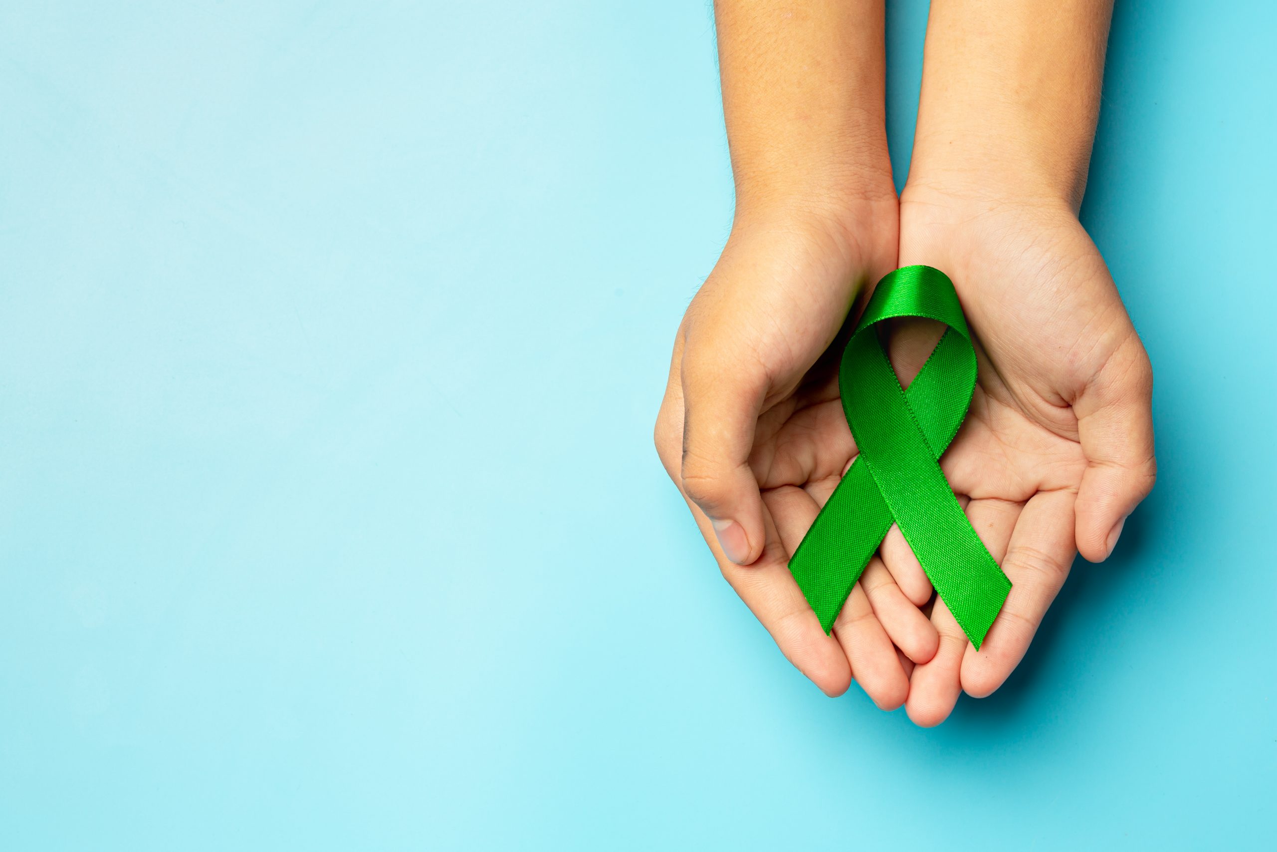 world mental health day green ribbon put human s hands blue background scaled 1